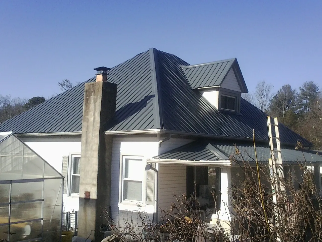 Dark blue standing seam metal roof on a white farmhouse with dormer — Slate & Tile Roof Repair by Roofing Brothers in Martinsville