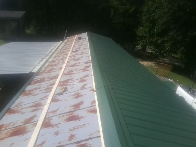 Old rusted panels beside newly installed green metal roofing — Wind Damage Roof Repair by Roofing Brothers in Martinsville