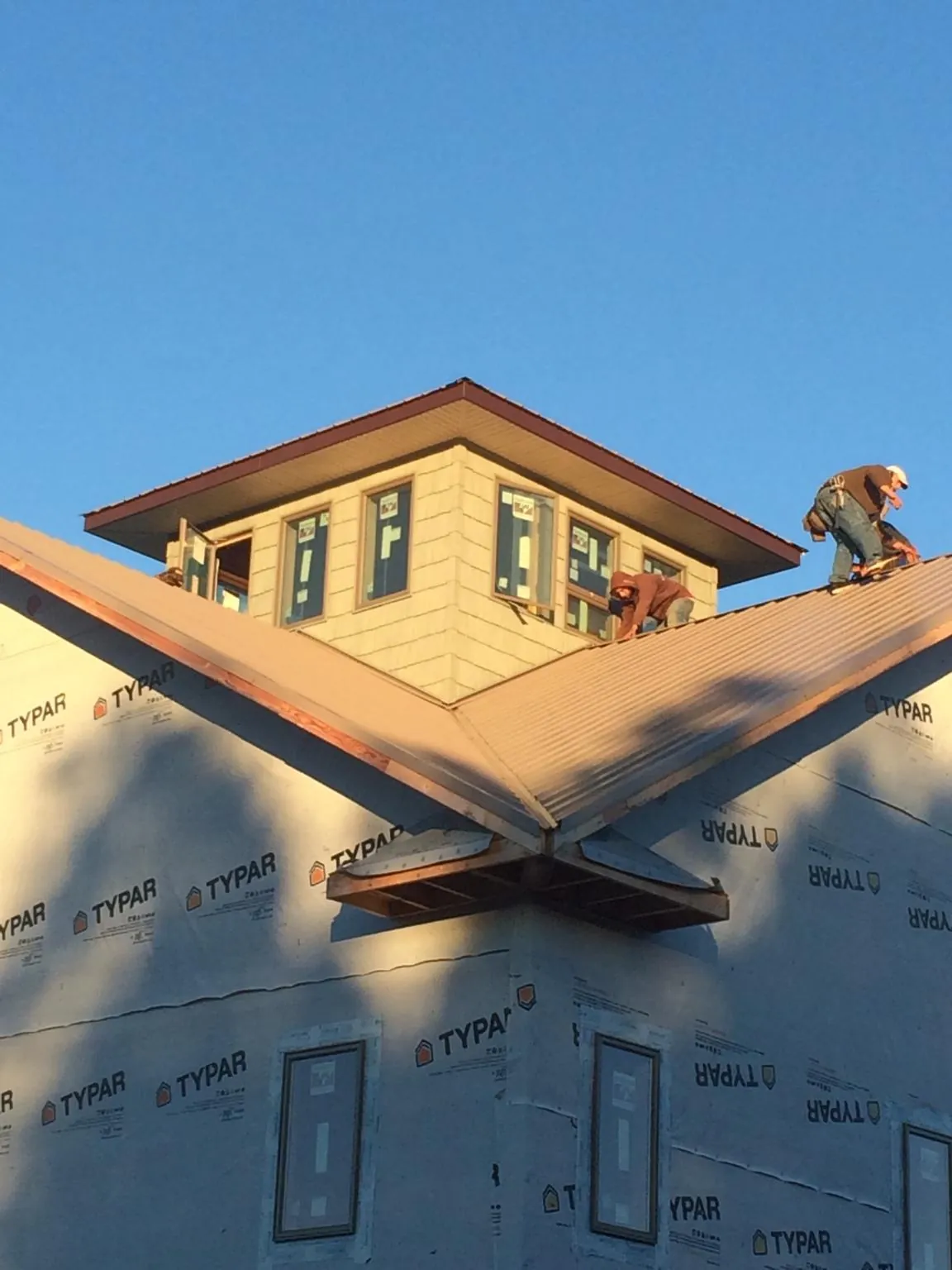 Roofers working around a rooftop cupola on a new metal roof at sunset — Roof Waterproofing in Martinsville by Roofing Brothers